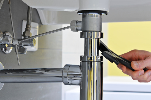 Close-up of plumber's hand doing repairing work at the sink.
