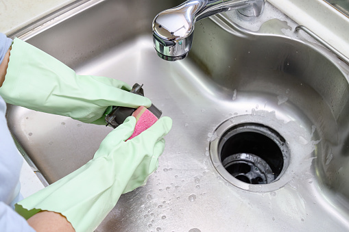 Women cleaning the kitchen sink with a sponge